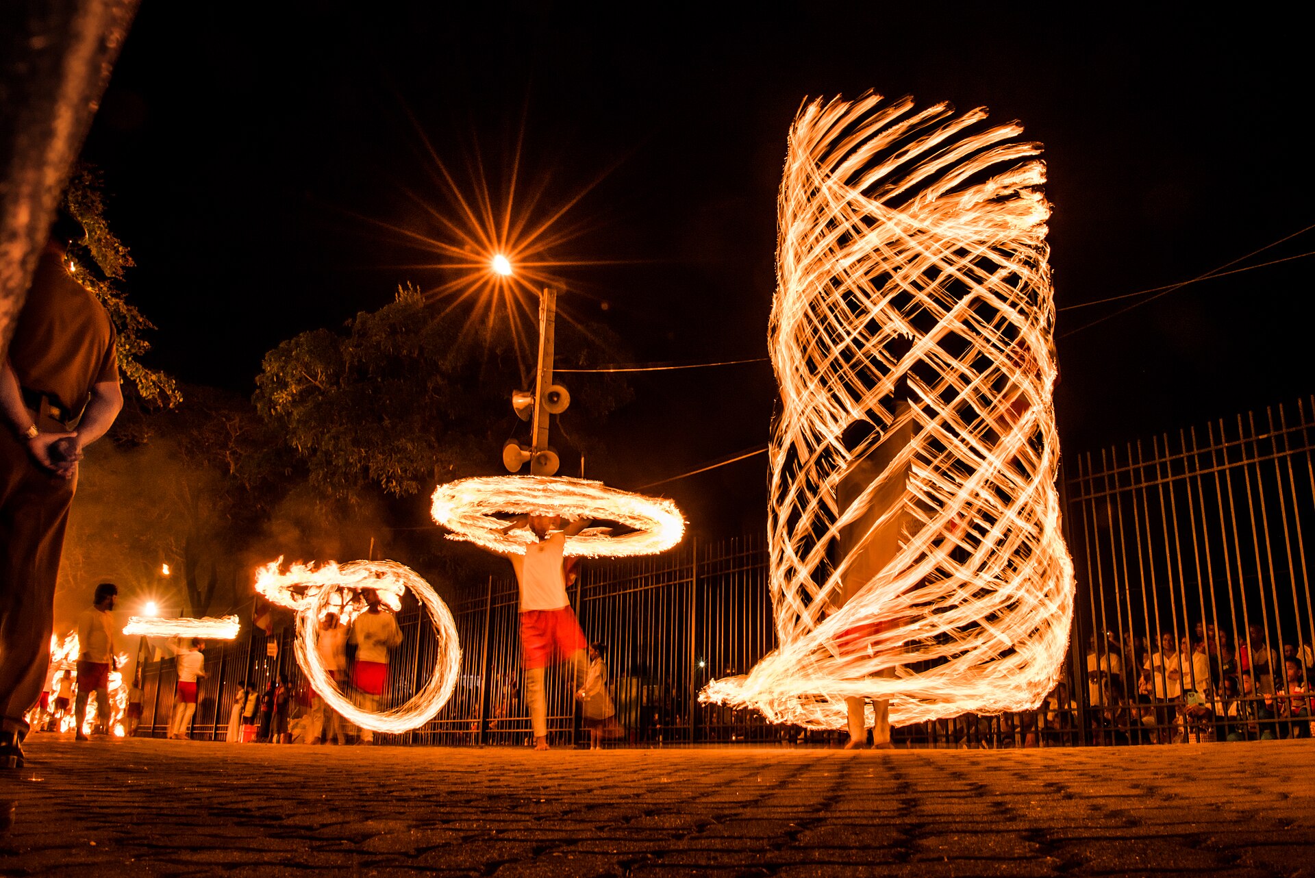 Fire dancers spinning flames during the night procession